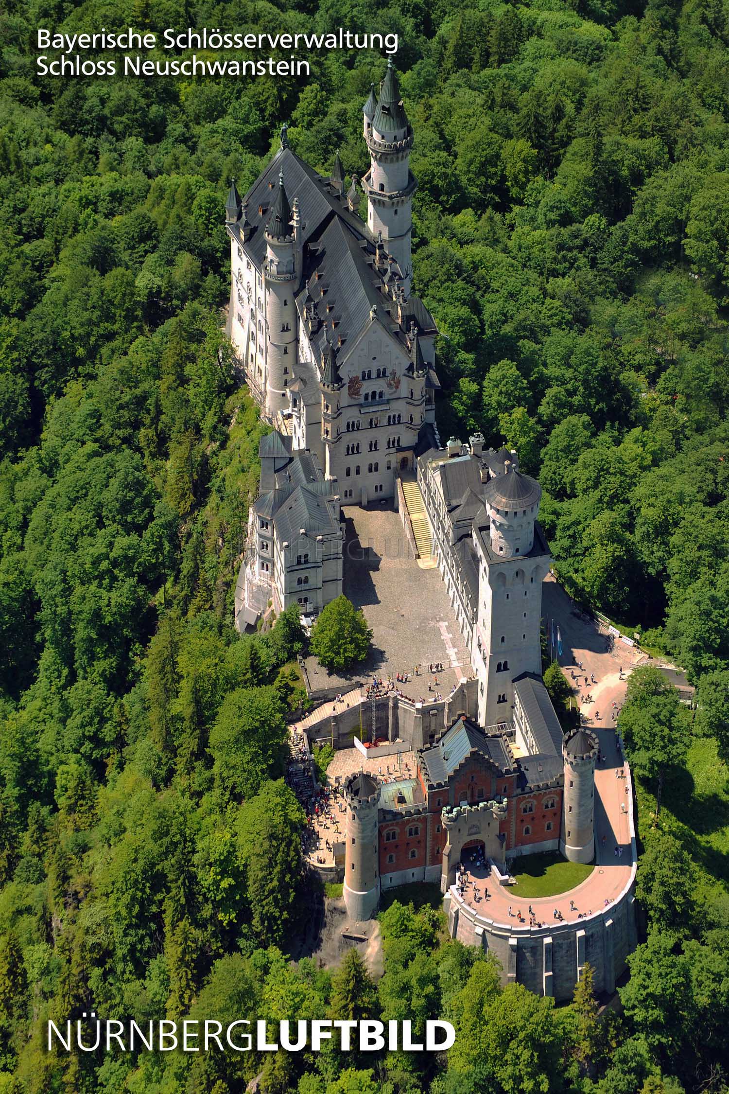 Luftbild von Schloss Neuschwanstein auf bewaldetem Bergrücken im Allgäu